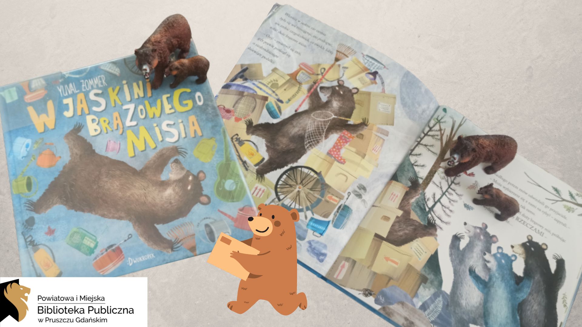 Zamknięta książka pt. „W jaskini brązowego misia” leży obok otwartej książki. Na okładce, jak też na otwartych stronach, są postaci niedźwiedzi wśród ogromnej ilości rzeczy. Na książkach stoją gumowe figurki niedźwiedzi. Pomiędzy książkami umieszczony jest animacja niedźwiedzia niosącego paczkę.