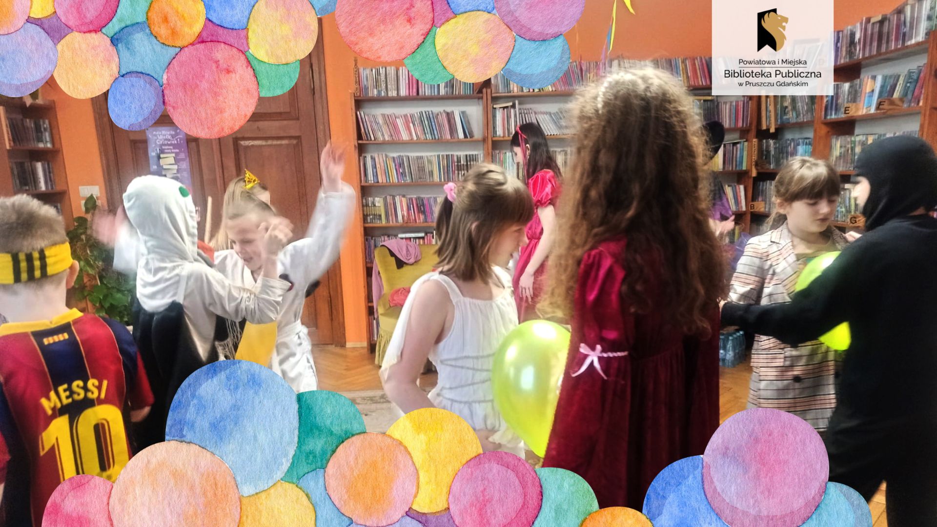 Grupa dzieci w kolorowych strojach tańczy podzielona w pary. Każda z par trzyma pomiędzy brzuchami balona.