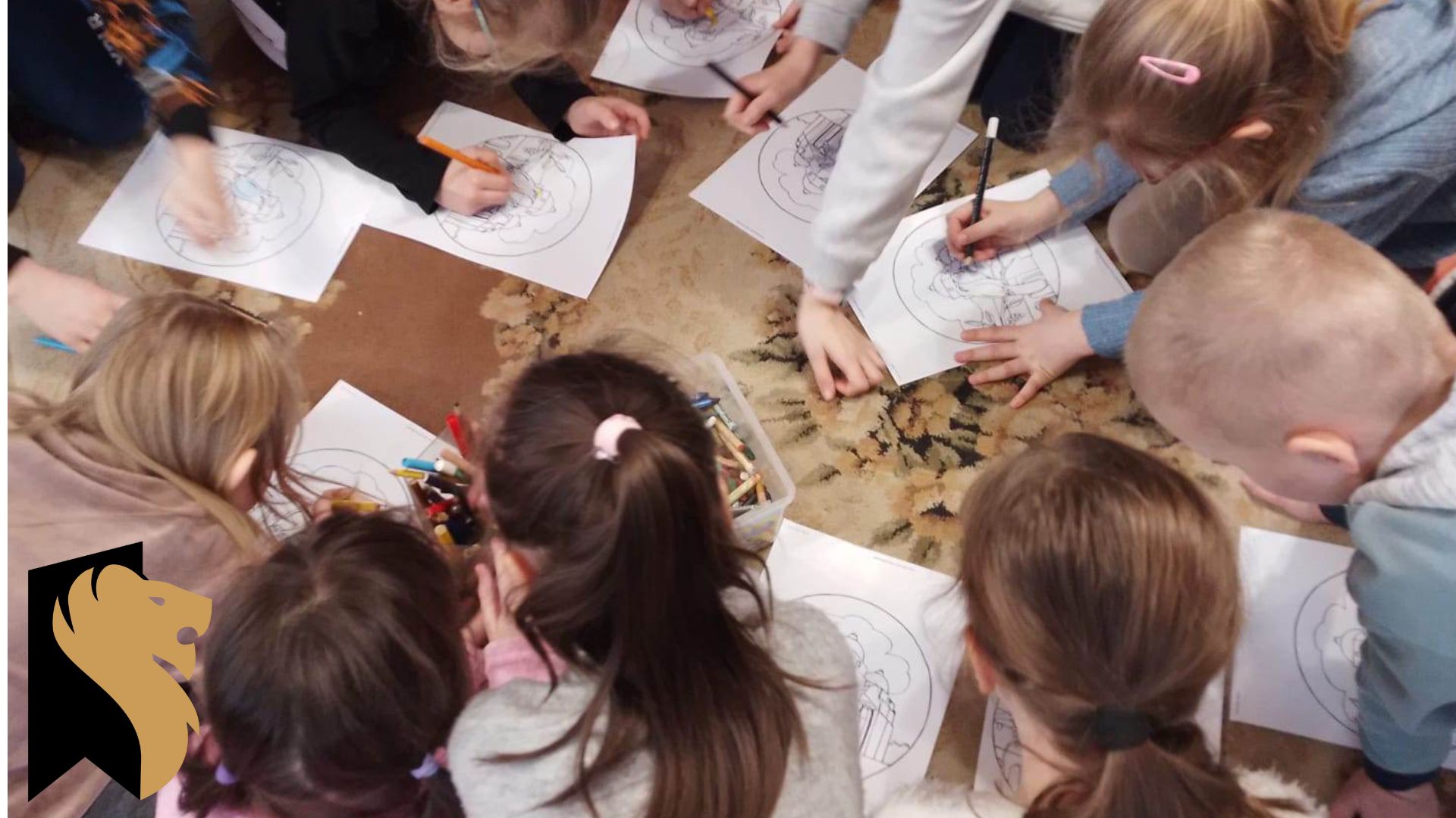 Grupa dzieci klęczy w okręgu na dywanie i koloruje zadrukowane kartki.