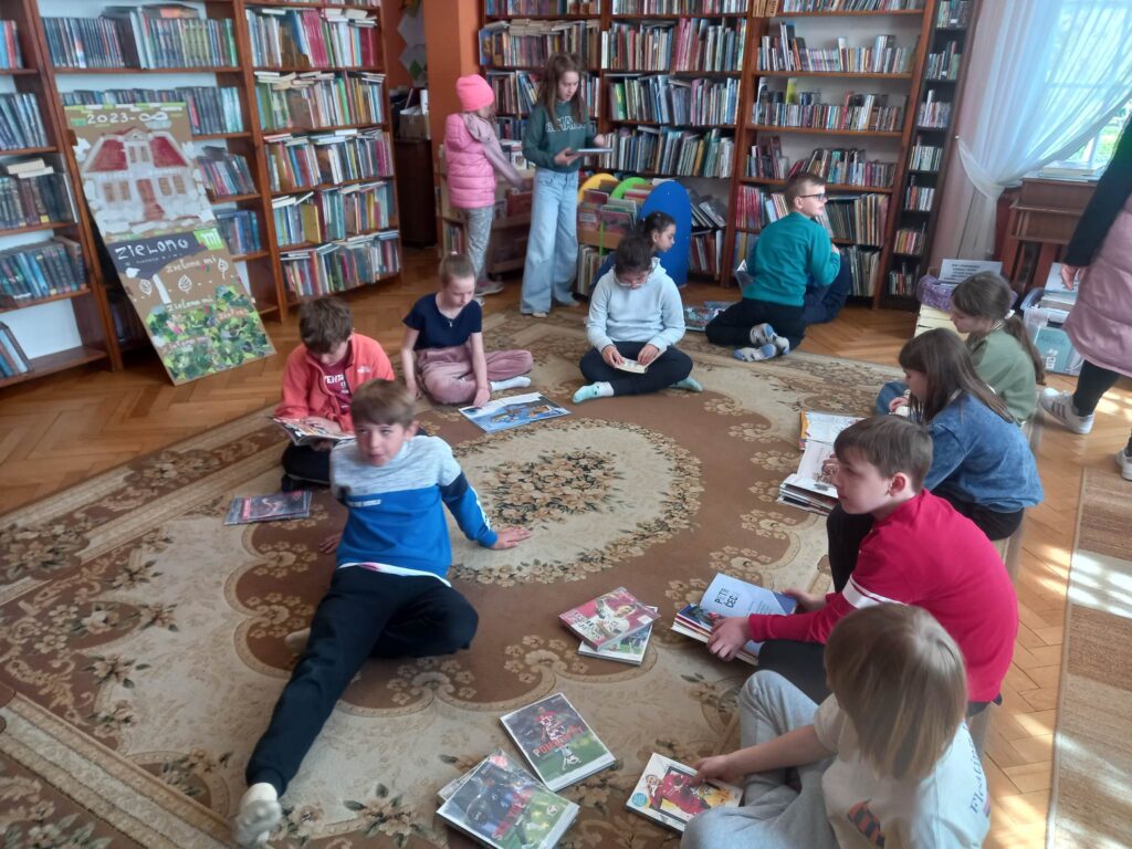 Na dywanie siedzą dzieci i oglądają książki.