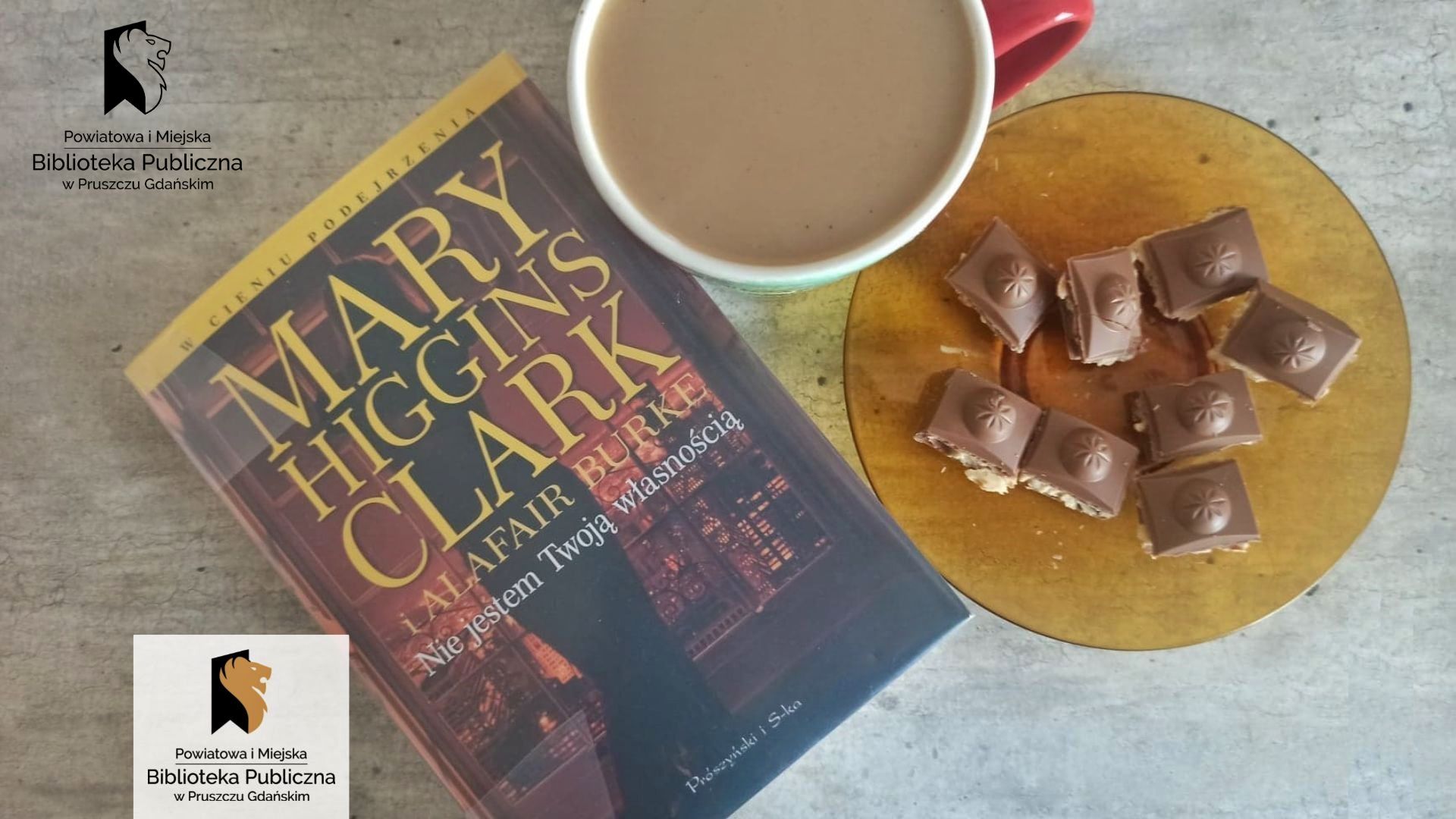 Książka Mary Higgins Clark pt. Nie jestem Twoją własnością. Z prawej strony filiżanką z kawą oraz talerzyk z kostkami czekolady.