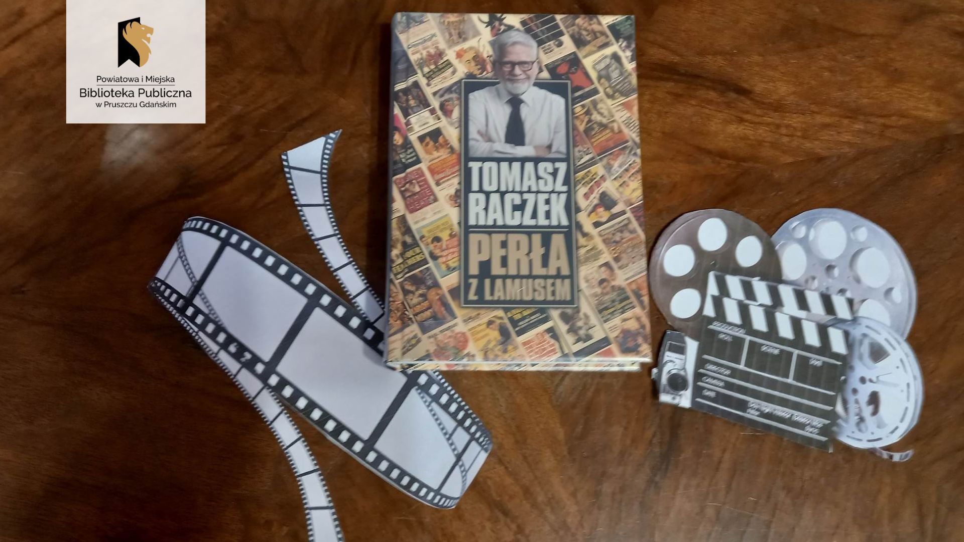 Na brązowym tle książka Tomasza Raczka „Perła z lamusem". Z jednej strony położona klisza filmowa, z drugiej kamera