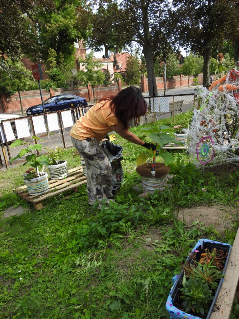 Olena Ulianova z Fundacji KIWI podlewa rośliny z mobilnego ogrodu.