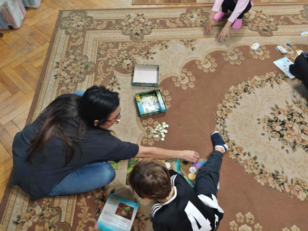 Chłopiec z mamą siedzą na podłodze i grają w grę.