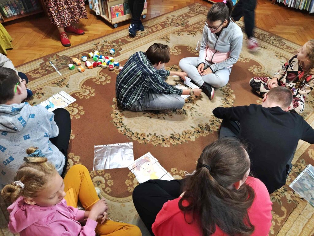 Dzieci siedzą na podłodze. Przed sobą mają układanki przedstawiające dzieci.