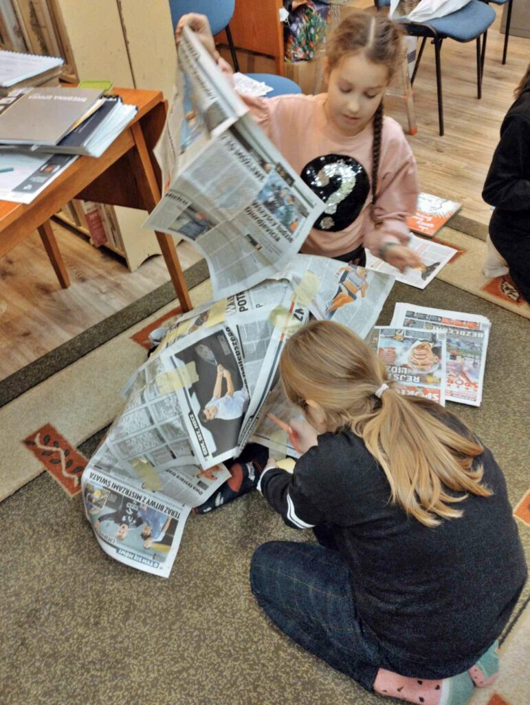 2 dziewczynki rozkładają gazety.