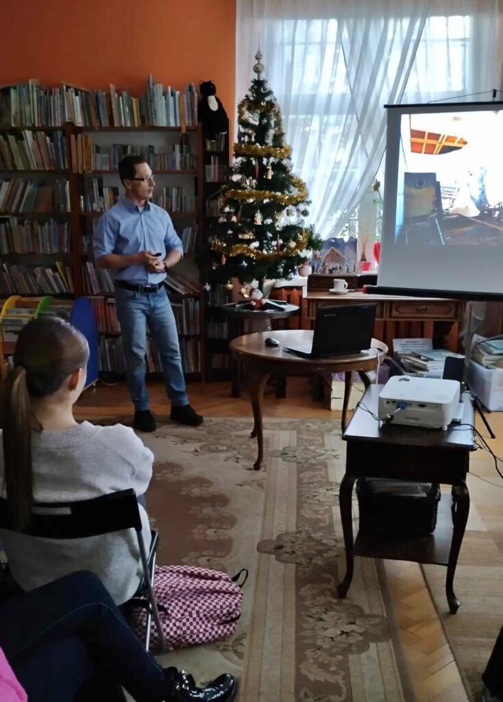 Tomasz Ilnicki wyświetla slajdy z wyprawy do Czarnobyla.  W spotkaniu uczestniczy młodzież.