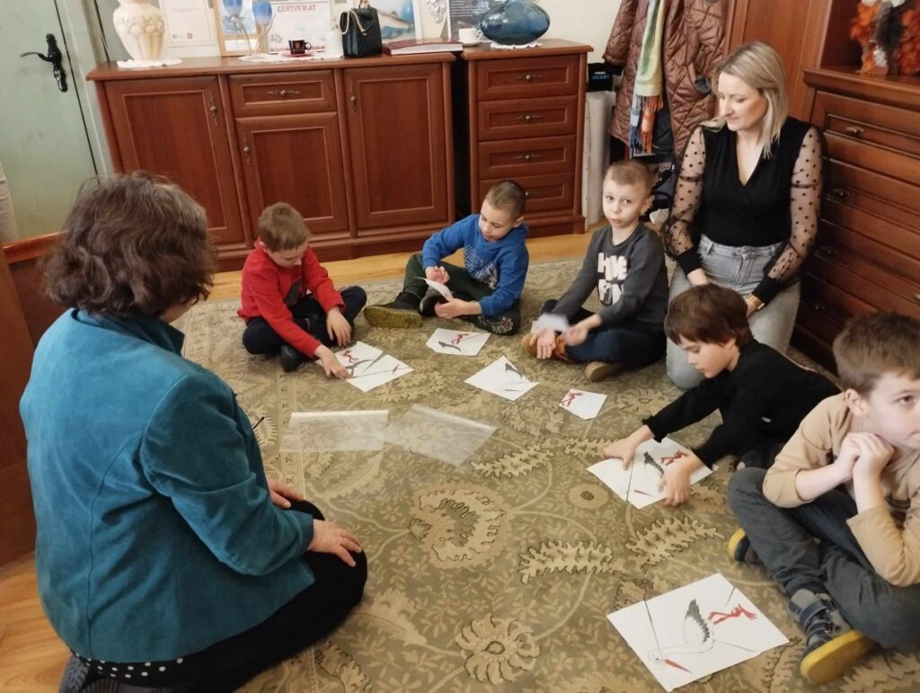 Dzieci układają papierowe puzzle z wizerunkiem bociana
