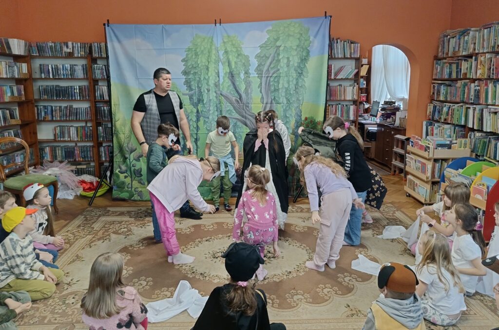 Dzieci w bibliotece podczas warsztatów teatralnych prowadzonych przez Sławomira Kochanka.