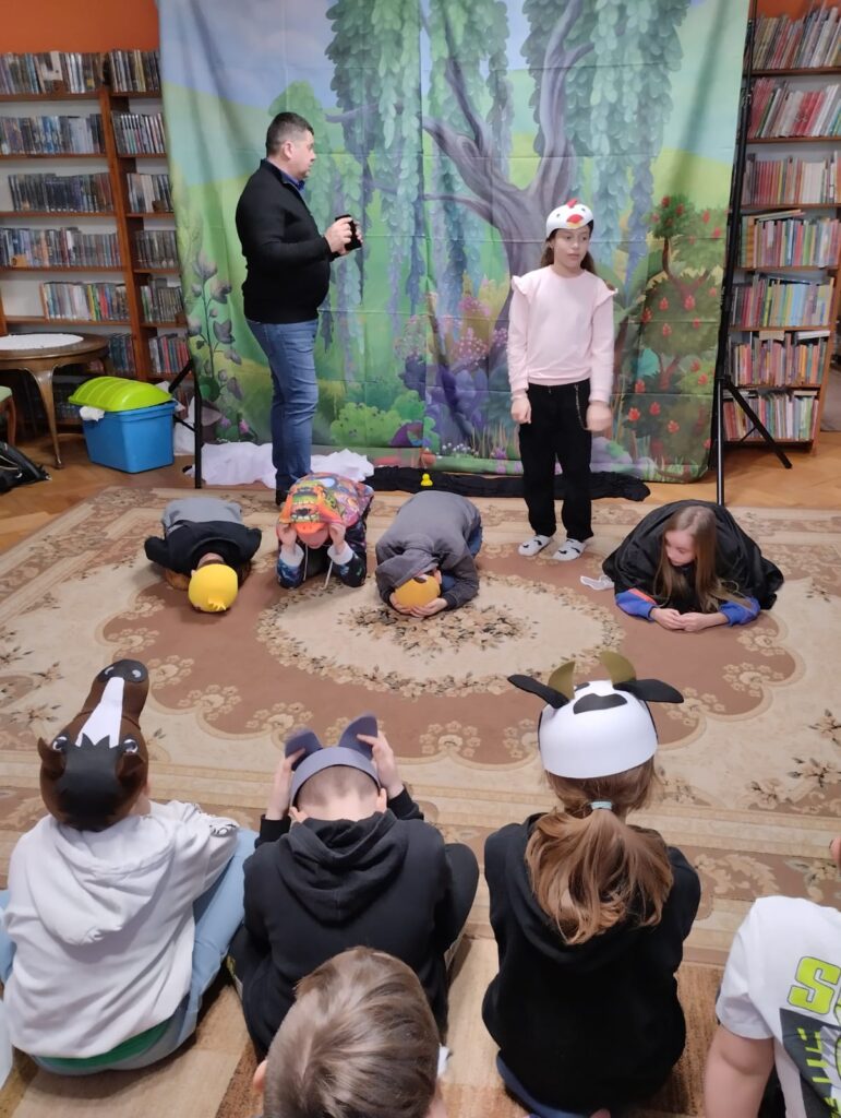 Dzieci na dywanie odgrywają scenę ze sztuki.
