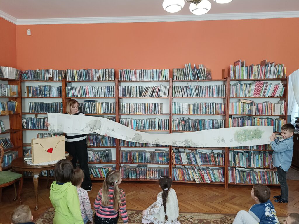 Bibliotekarka prezentuje najdłuższą książkę dostępną w bibliotece, książkę w kształcie harmonijki.