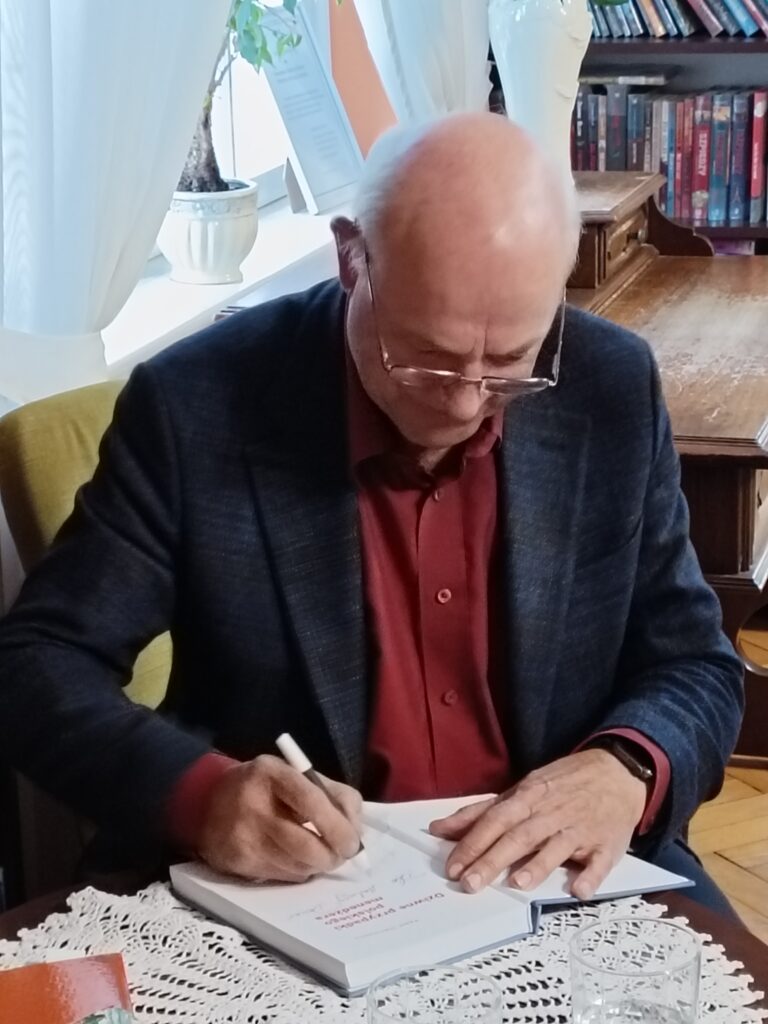Paweł Olechnowicz podpisujący swoją książkę.