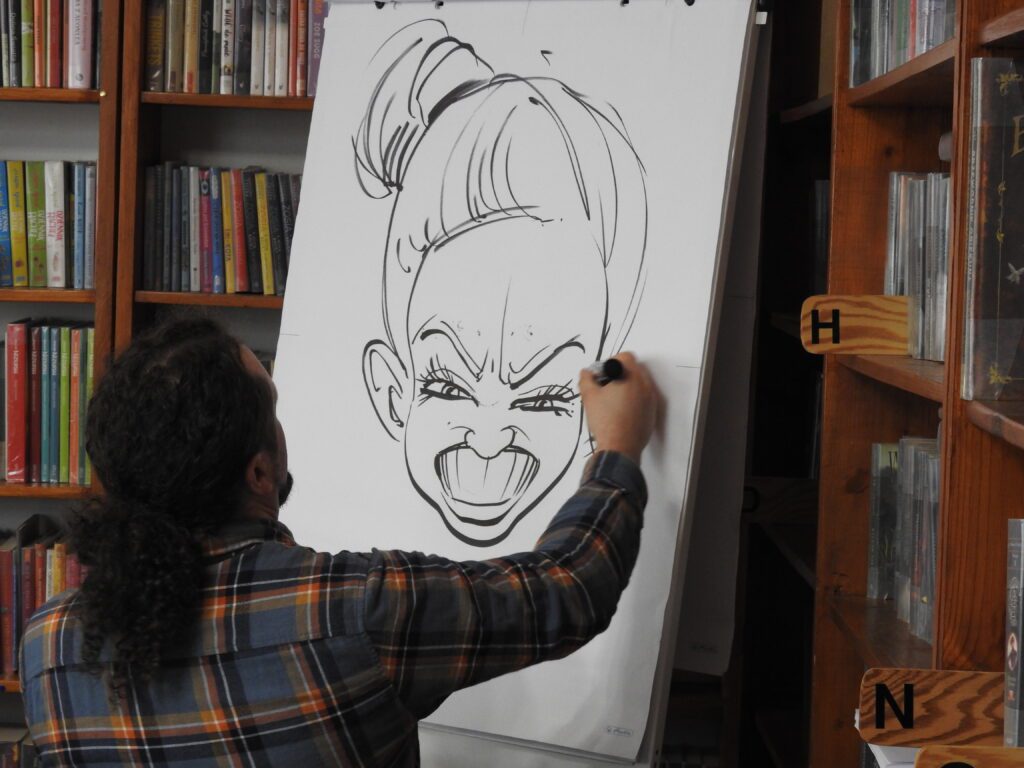 Szymon Teluk rysuje na sztaludze karykaturę.