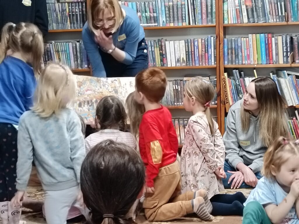 Bibliotekarka pokazująca dzieciom ilustracje .