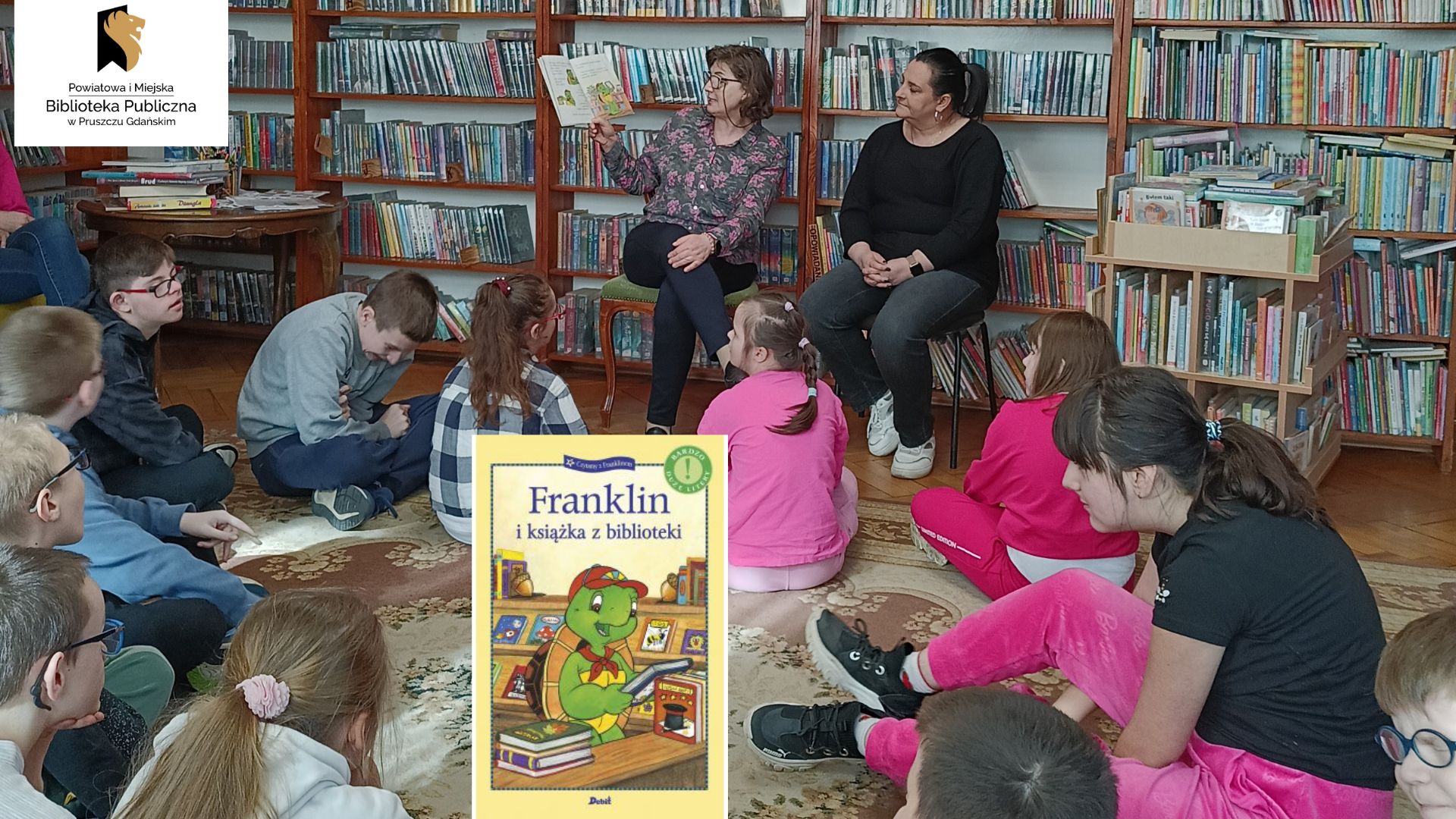 Dzieci siedzą tyłem na dywanie. Patrzą na bibliotekarki siedzące przed nimi na krzesłach. Kobieta trzyma w górze otwartą książkę.