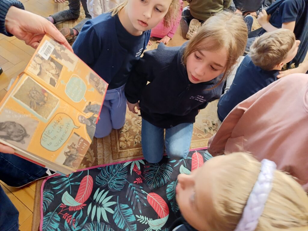 Dzieci oglądające ilustracje w książce.