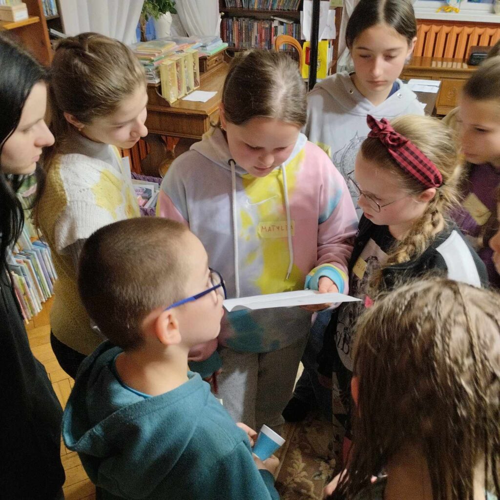 Grupa dziewczynek rozwiązująca zadanie w bibliotece.