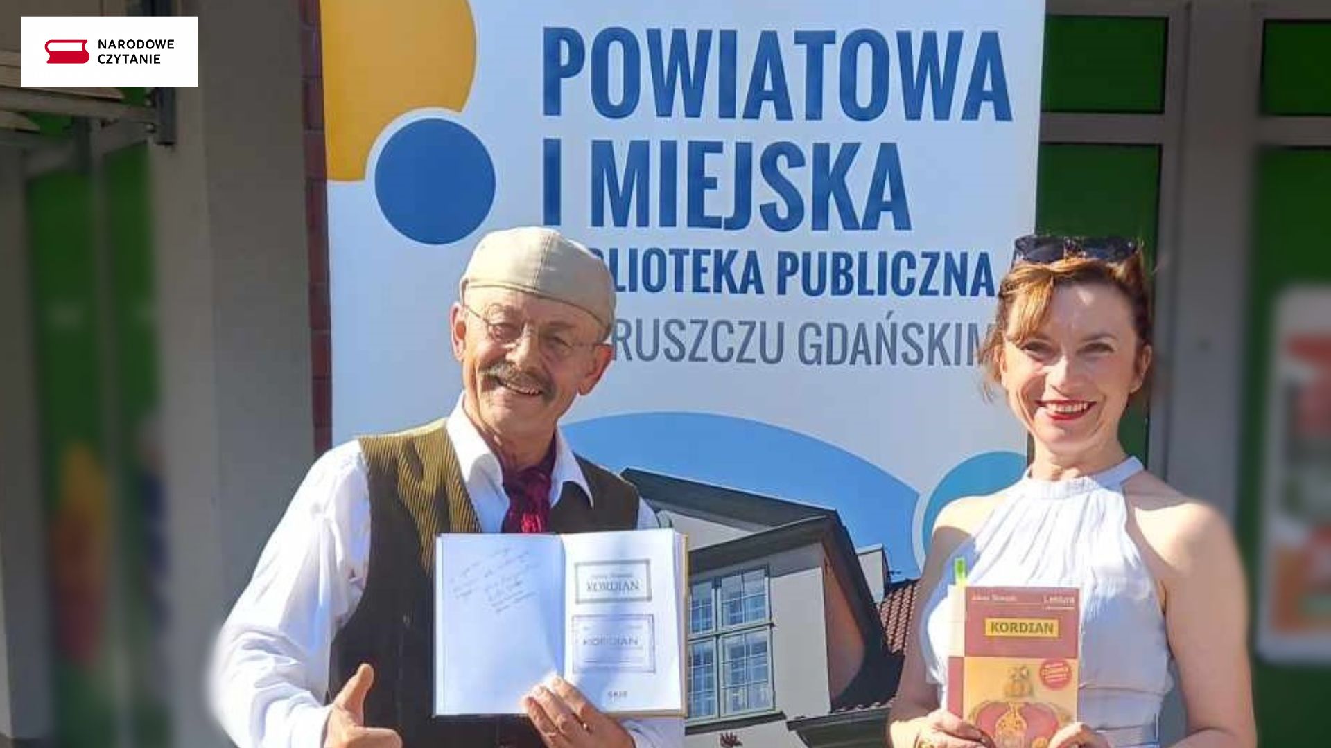 Daniel Saulski i Anna Kinga Osior pozują do zdjęcia z książką Juliusz Słowackiego pt. Kordian. W tle baner biblioteki.