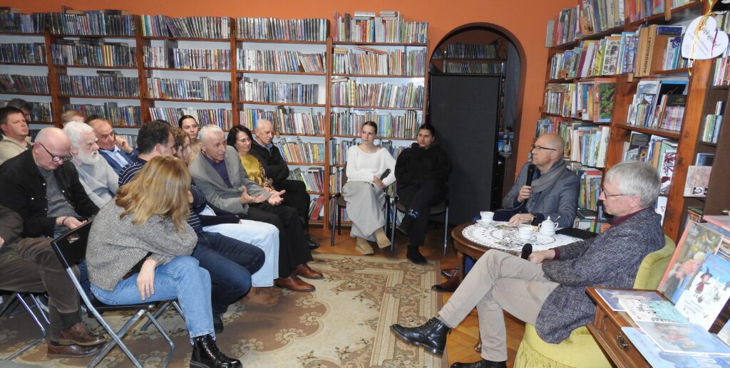 Sala biblioteczna. Na krzesłach siedzą uczestnicy Biesiady Literackiej. Przed uczestnikami siedzi prowadzący spotkanie Krystian Nehrebecki oraz gość Peter Olivier Loew.